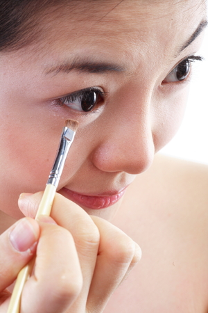 Beauty Concept - Close up shot of Asian woman applying makeup with make up toolsの写真素材