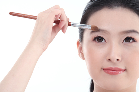 Beauty Concept - Young Asian woman applying make up with make up toolsの写真素材