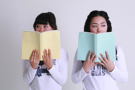 Asian female students reading books - isolated on whiteの写真素材