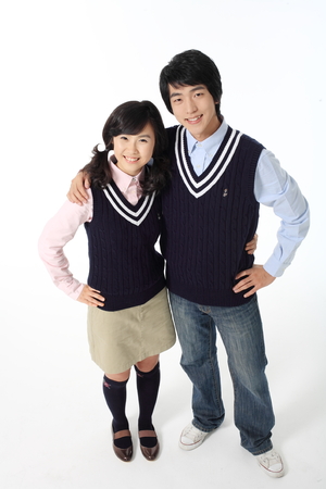 Asian girl and boy students standing and the boy putting his arm on her shoulder in the studio, lsolated on whiteのeditorial素材