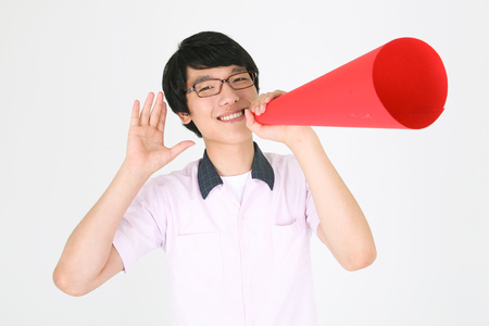 An Asian boy student shouting through the red corn in the stuido, isolated on whiteの写真素材