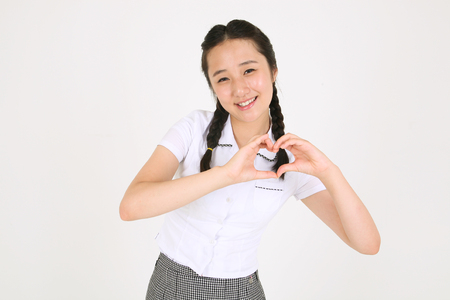 An Asian girl student student making heart with her hands in ther studio, isolated on white.の写真素材