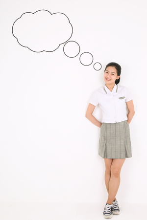 A cute Asian girl student in front of the speech background wall with lovely smile in the studio, isolated on white.の写真素材