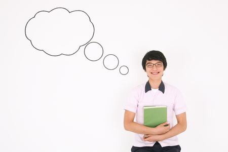 A Asian boy student in front of the speech background holding a book smiling in the studio, isolated on white.の写真素材