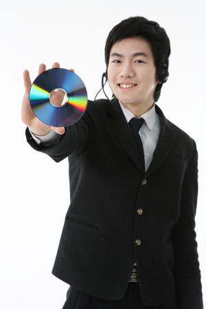 An Asian boy student holding a CD with cheerful smile in the studio, isolated on white.の写真素材