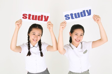 Two Asian girl students holding a study sign in the studio, isolated on white.の写真素材