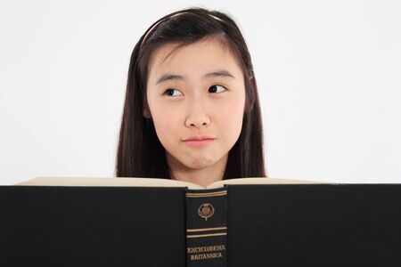 Young Asian girl student with a book in the studio, isolated on whiteのeditorial素材