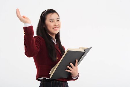 Young Asian girl student with a book in the studio, isolated on whiteの写真素材