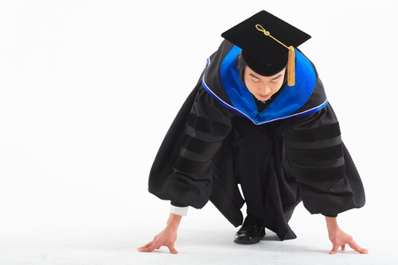 An Asian man with a graduation hat and clothes in the studio, isolated on whiteの写真素材