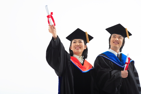 An Asian woman and a man with a graduation hat and clothes in the studio, isolated on whiteの写真素材