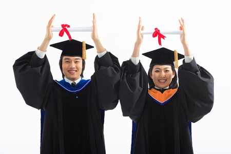 An Asian woman and a man with a graduation hat and clothes in the studio, isolated on whiteの写真素材