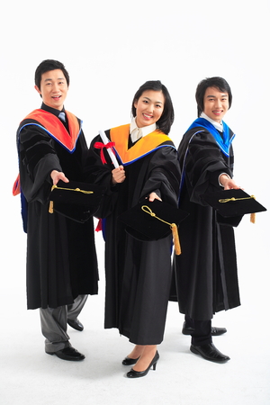Two Asian men and a woman with graduation clothes and a graduation hat in the studio, isolated on white.の写真素材