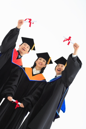 Two Asian men and a woman with graduation clothes and a graduation hat in the studio, isolated on white.の写真素材