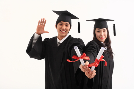 An Asian woman and a man with a graduation hat and clothes in the studio, isolated on whiteの写真素材