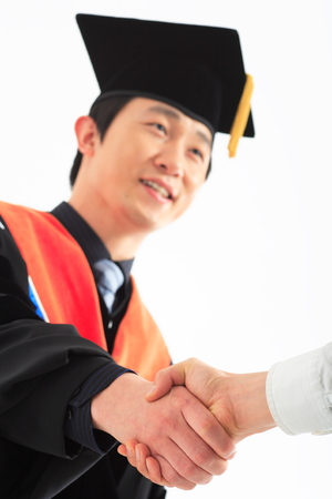 An Asian man with a graduation hat and clothes in the studio, isolated on whiteの写真素材