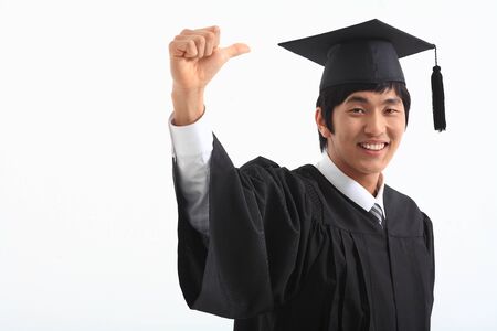 An Asian man with a graduation hat and clothes in the studio, isolated on whiteの写真素材