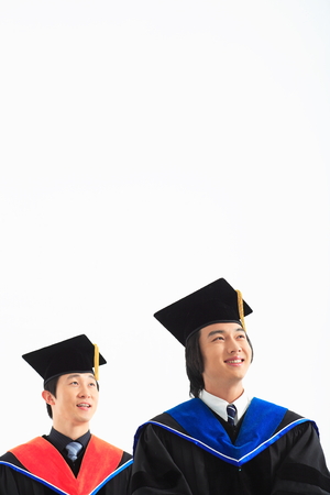 Two Asian men with a graduation hat and clothes in the studio, isolated on whiteの写真素材