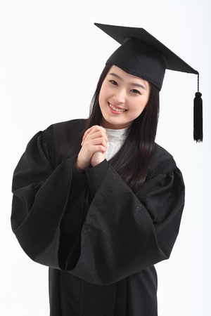 An Asian woman with a graduation hat and clothes in the studio, isolated on whiteの写真素材