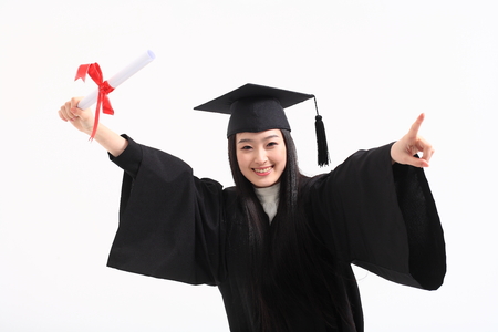 An Asian woman with a graduation hat and clothes in the studio, isolated on whiteの写真素材