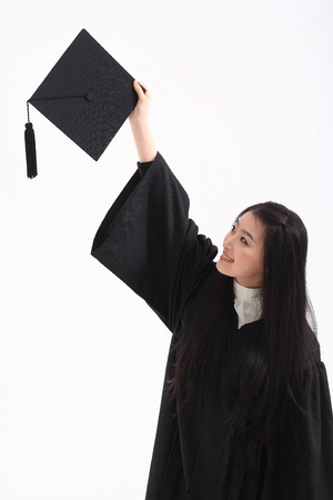 An Asian woman with a graduation hat and clothes in the studio, isolated on whiteの写真素材