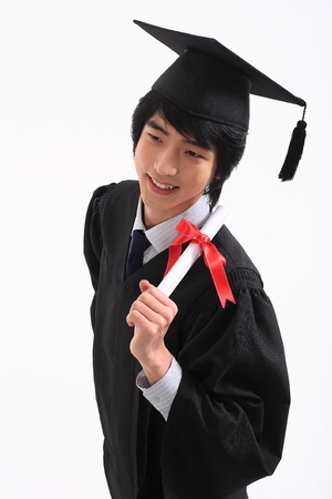 An Asian man with a graduation hat and clothes in the studio, isolated on whiteの写真素材