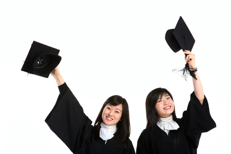 Two Asian women with a graduation hat and clothes in the studio, isolated on whiteの写真素材