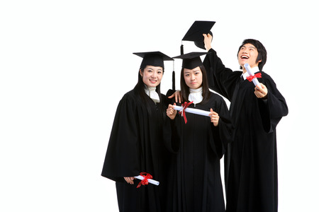 Two Asian women and a man with a graduation hat and clothes in the studio, isolated on white.の写真素材