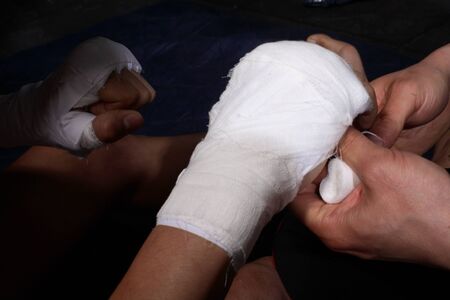 Wrapping a bandage on a fighter's arm, boxing, kickboxing, Muay Thai - isolated on whiteの写真素材