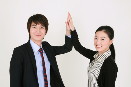 Well dressed young Asian couple giving a high five - isolated on whiteの写真素材