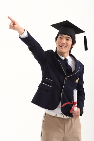 Asian male student wearing graduation cap posing with graduation certificate - isolated on whiteのeditorial素材