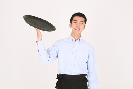 Young Asian waiter in a studio - isolated on whiteの写真素材