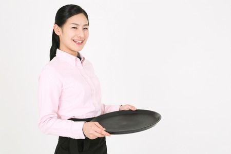 Beautiful young Asian waitress in a studio - isolated on whiteの写真素材