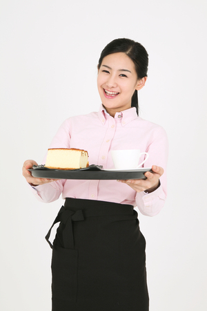 Beautiful young Asian waitress in a studio - isolated on whiteの写真素材