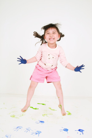 A little asian girl jumping with painted palms and soles - isolated on whiteの写真素材