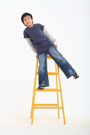 A asian boy posing leaning ladder - isolated on whiteの写真素材