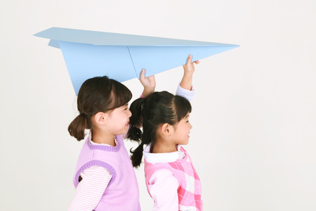 Two Asian girls posing with paper airplane - isolated on whiteの写真素材