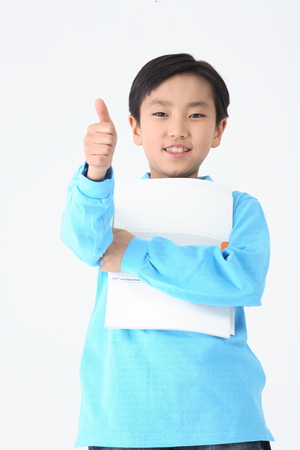 An Asian boy giving thumbs up with notebook - isolated on whiteの写真素材