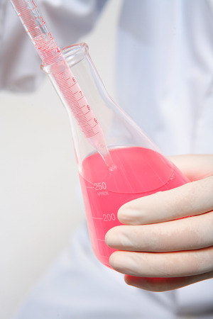 Close-up shot of hands holding a flask and a lab spuitの写真素材