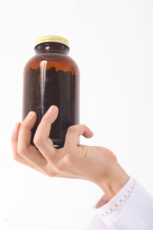 Close-up shot of a hand holding a jar of pillsの写真素材