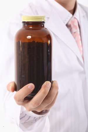 Close-up shot of a hand holding a jar of pillsの写真素材