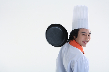 Back shot of a male cook holding a frying panの写真素材