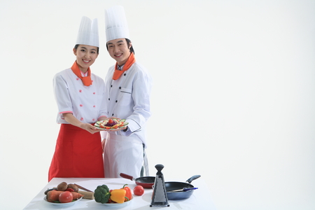 A couple of cooks presenting a plate of saladの写真素材