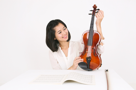 A female violinist sitting at the desk as holding a violinの写真素材