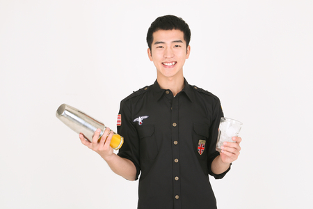 A male bartender making cocktail with a shaker and iceの写真素材