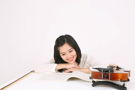 A female violinist sitting at the desk as resting her chin on handsの写真素材