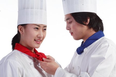 Close up shot of a male cook tying a scarf for a female cookの写真素材