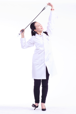 A female doctor holding a stethoscope and a injection in each hand over headの写真素材