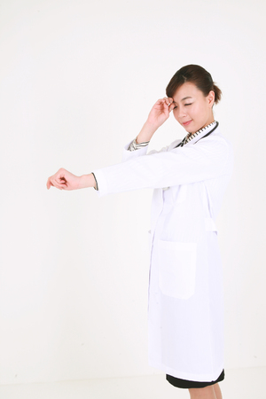 A female doctor stretching one arm as scratching her eyeの写真素材