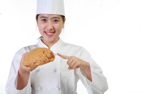 Close up shot of a female patissier holding bun and pointing itの写真素材