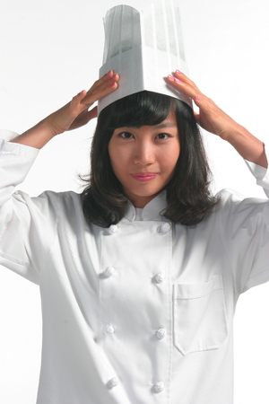 Close up shot of a female cook fixing her chef hat with both handsの写真素材